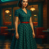 Frau im 50er-Jahre-Kleid mit rotem Gürtel vor einem leuchtenden Retro-Diner bei Nacht